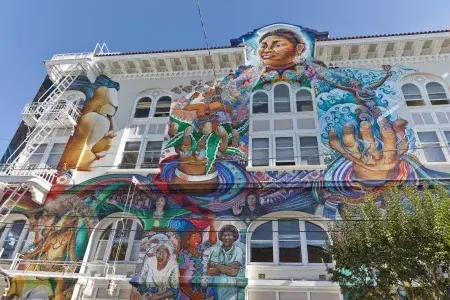 Un mural colorido y de gran escala cubre el costado del Edificio de Mujeres en el Distrito de la Misión de San Francisco.